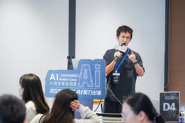 講者在 AI Builder Camp 標示旁手持咪高峰講解