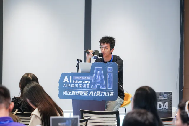 講者坐在電腦旁，手持咪高峰向學員說明